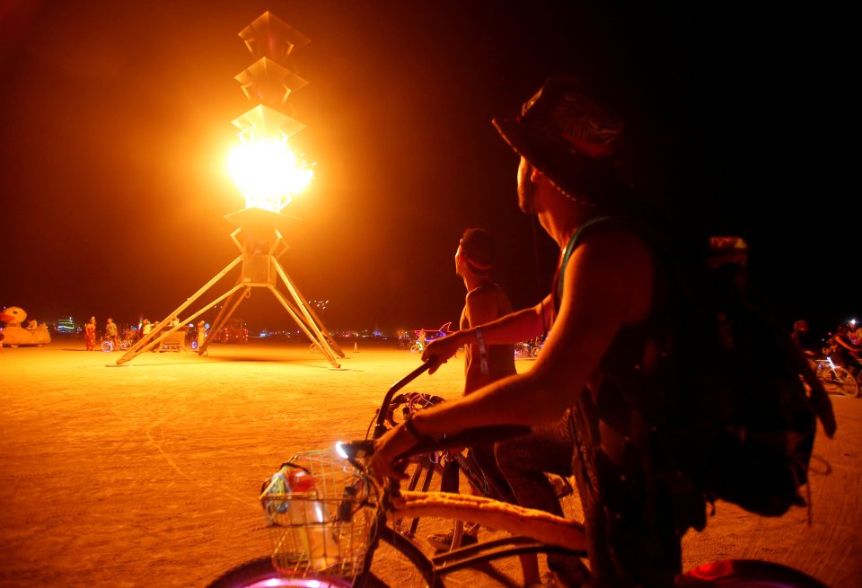 Participants watch the flames on the Spire of Fire as approximately 70,000 people from all over the world gather for the 30th annual Burning Man arts and music festival in the Black Rock Desert of Nevada